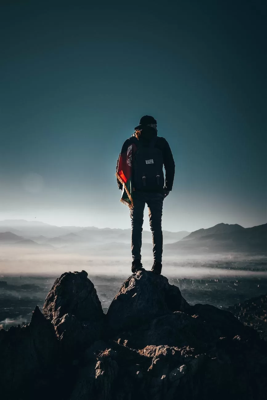 man carrying backpack standing on rock formation